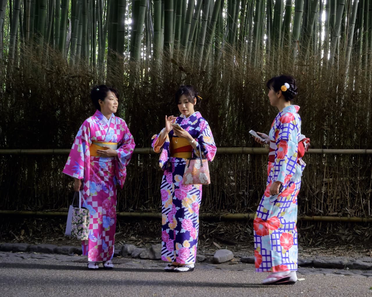 Three women in rented kimono walking a stone-paved historic street in Kyoto