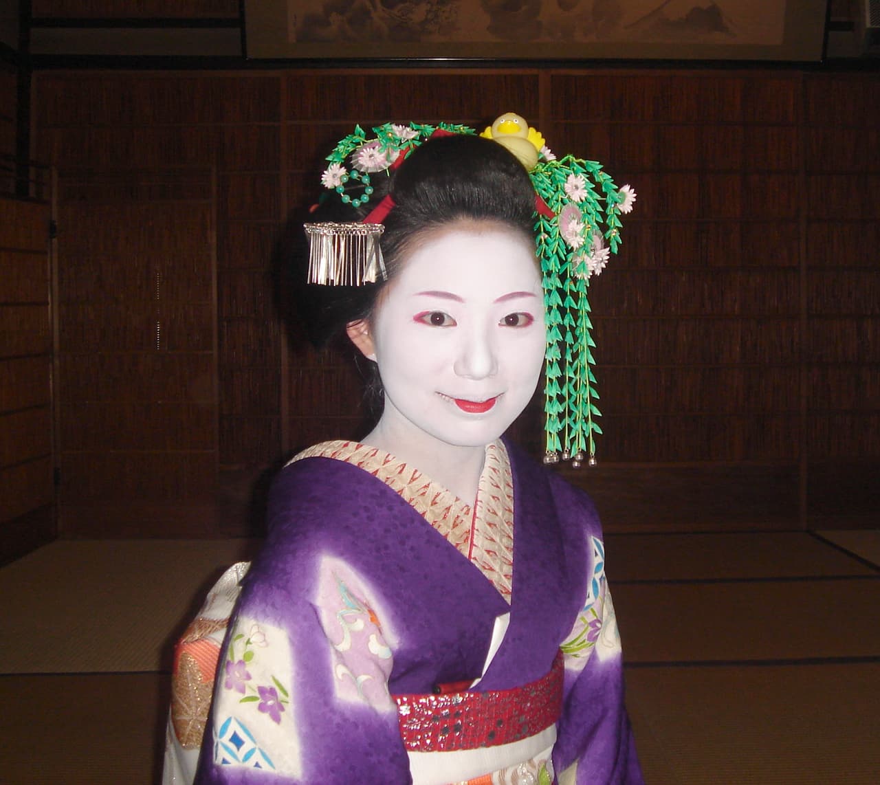 A maiko in colourful kimono and tall okobo clogs walking through Gion, Kyoto