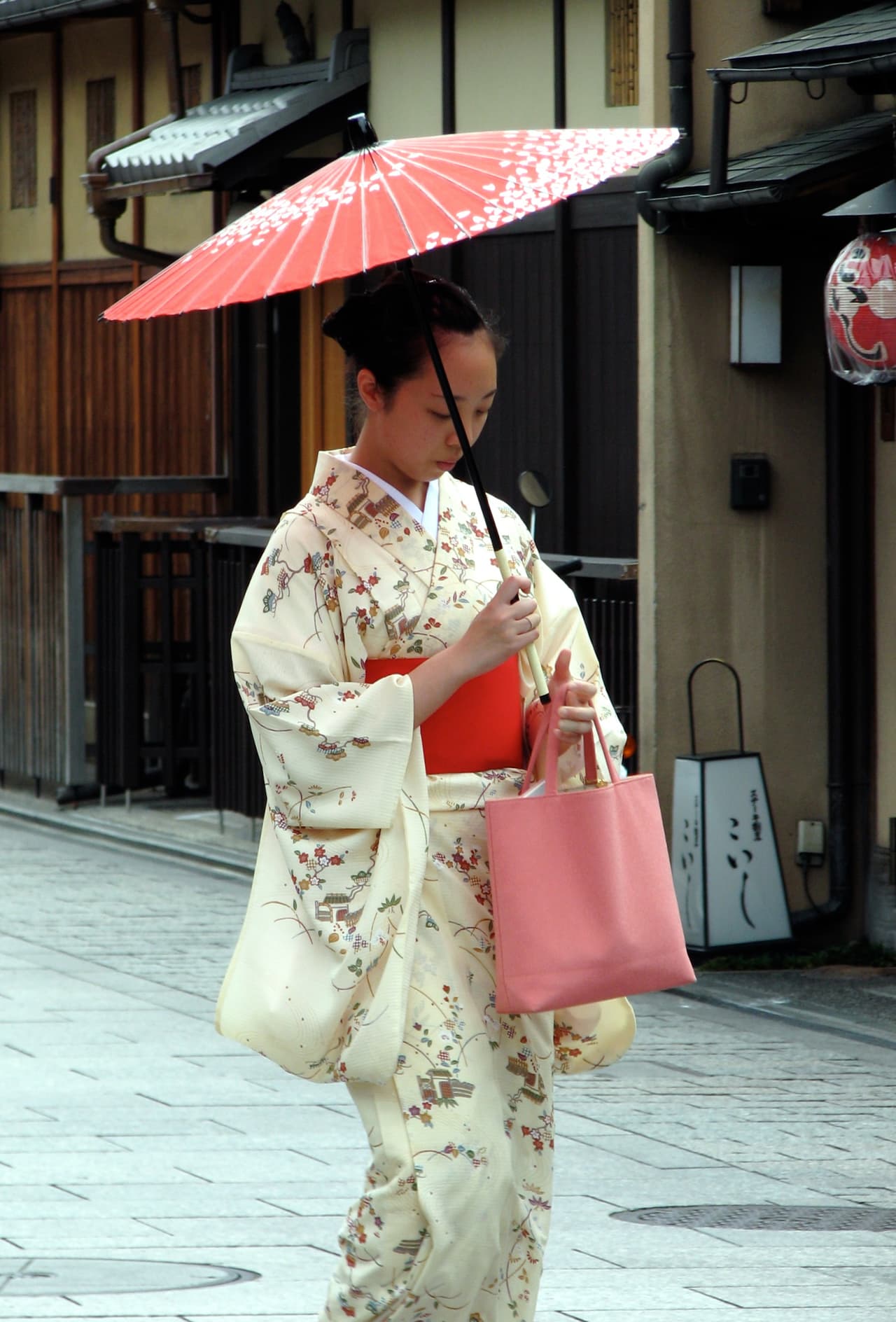 A woman in kimono walking a historic street in the Gion district of Kyoto