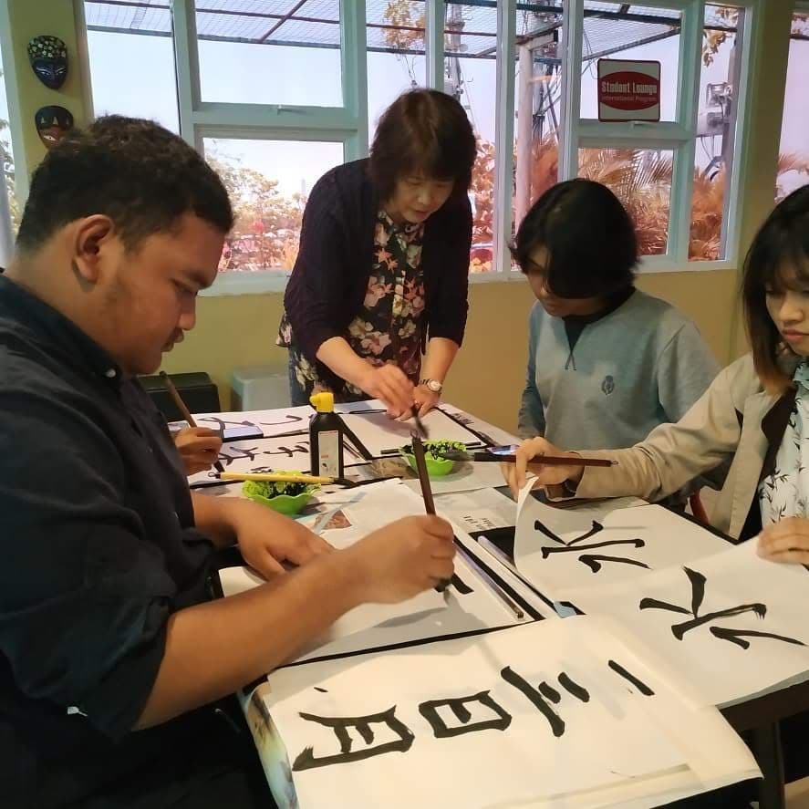 A hand writing Japanese kanji with an ink-loaded fude brush — shodō calligraphy in action